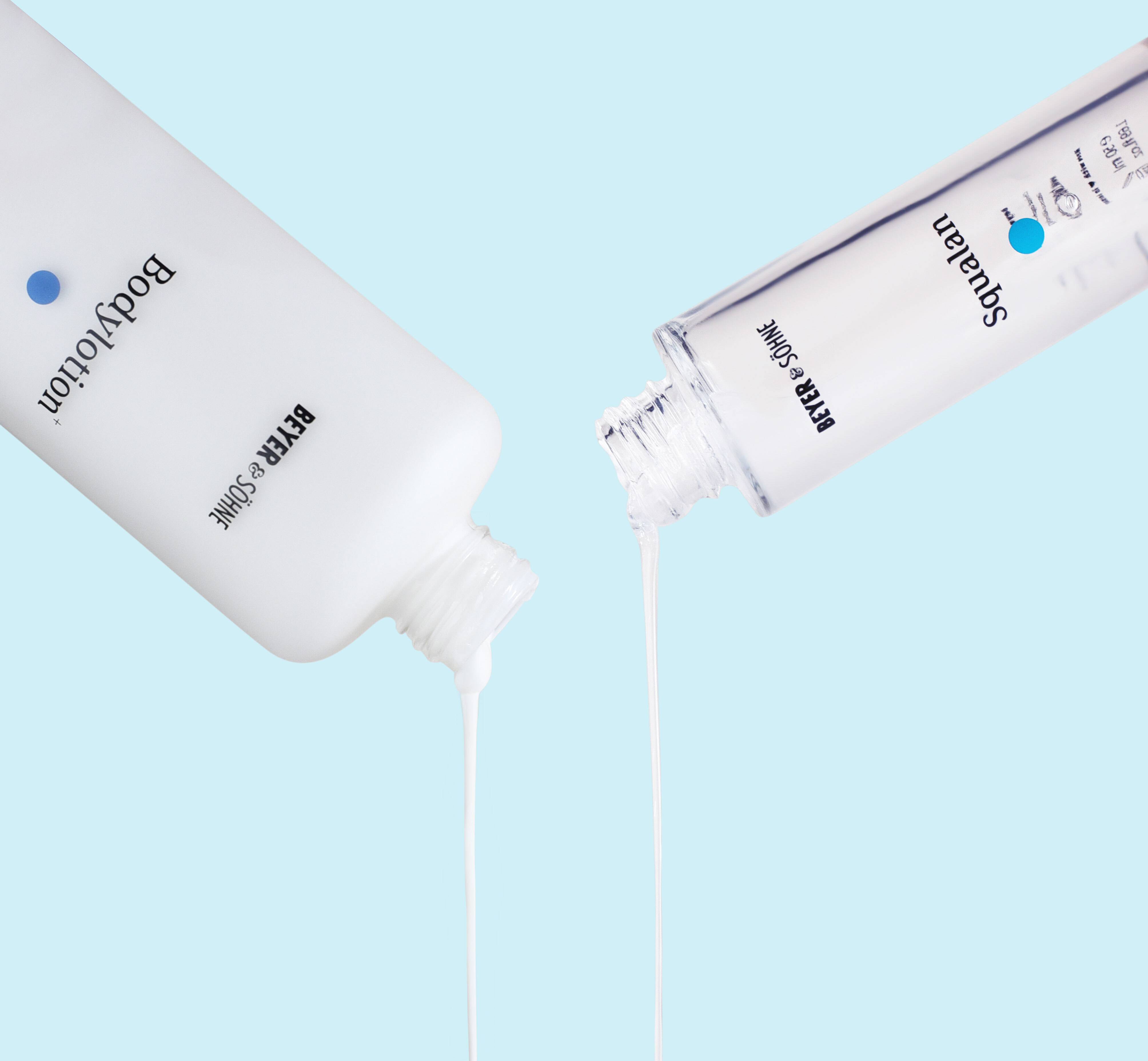 Beyer & Söhne Bodylotion und Squalan werden gleichzeitig aus dem Spender gegossen, vor hellblauem Hintergrund.